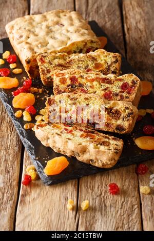 Homemade winter fruit muffin with dried apricots berries raisins figs cherries closeup on a slate board on the table. vertical Stock Photo
