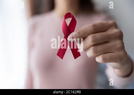 Close up female hand holding red awareness ribbon
