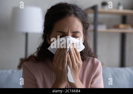 Close up sick woman blowing nose, holding paper tissue