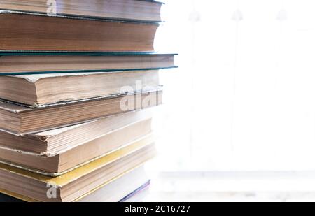 A stack of old books lying on a windowsill Stock Photo