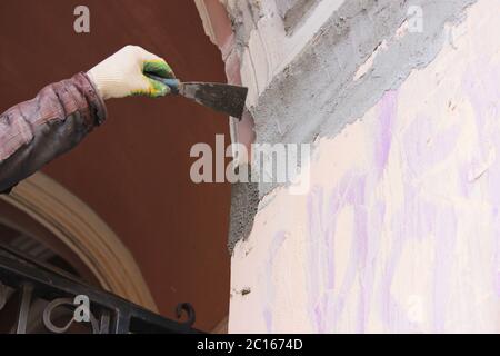 Construction worker wearing worker overall with wall plastering tools renovating apartment house. Plasterer renovating outdoor w Stock Photo