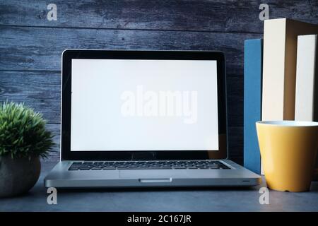 Laptop with blank screen and stack of books on table. Stock Photo
