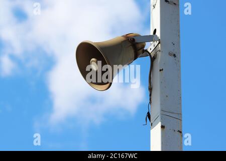 Loudspeaker on a pole in a railway station against a blue sky. Stock Photo