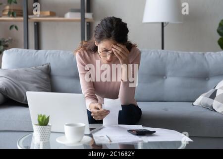 Stressed woman wearing glasses checking bills, debt or bankruptcy Stock Photo