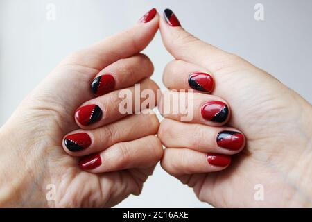 beauty delicate red-black manicure with gel varnish on a white wall background Stock Photo