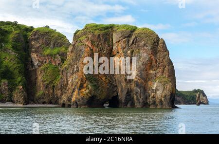 Rocks with caves and grottoes in Avacha Bay of Pacific Ocean. The coast of Kamchatka. Stock Photo