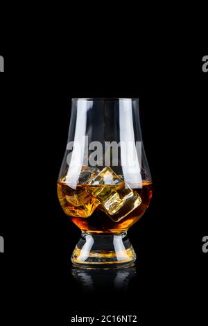 Glass of whiskey or other alcohol with cube ice on black background