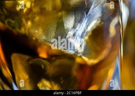 Pieces of ice cube in whiskey. Close up macro of Ice cubes in glass drink or another alcohol. Abstract texture background Stock Photo
