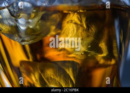 Pieces of ice cube in whiskey. Close up macro of Ice cubes in glass drink or another alcohol. Abstract texture background Stock Photo