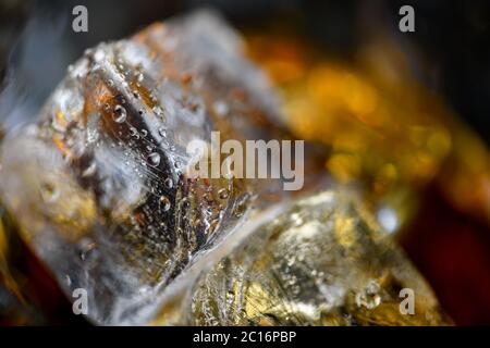 Pieces of ice cube in whiskey. Close up macro of Ice cubes in glass drink or another alcohol. Abstract texture background Stock Photo