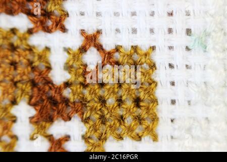 Macro shot fragment embroidery pattern brown thread handmade embroidery, pattern in cross-stitch style on white fabric Stock Photo