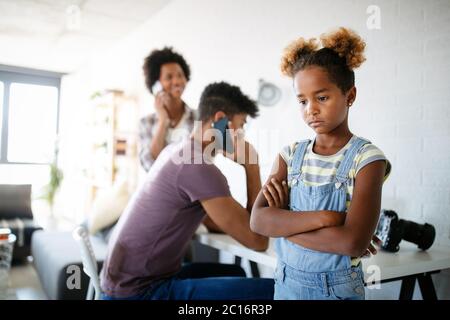 Frustrated sad child looking for attention from busy working parents Stock Photo