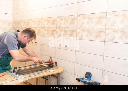 Tile cutting machine. Construction worker. Precise cutting of ceramic tiles. Stock Photo