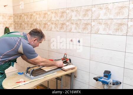 Tile cutting machine. Construction worker. Precise cutting of ceramic tiles. Stock Photo