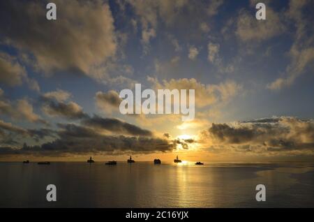 Awesome sunrise with beautiful sky of scattered clouds, calm sea and many ships in the bay Stock Photo