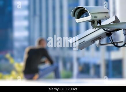 security CCTV camera or surveillance system with young man on blurry background Stock Photo