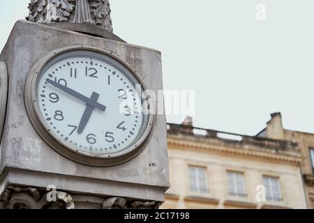 Large white clock face on a stone clock column in Place de la Comédie, Bordeaux, France Stock Photo