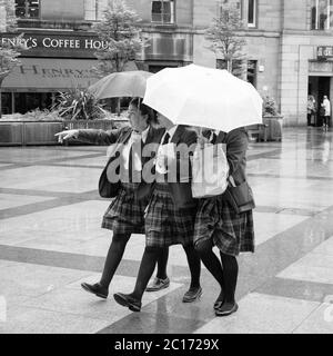 Monochrome (black and white) image of three pupils of Dundee High School in City Square, Dundee after the school's graduation ceremony in the Caird Hall.