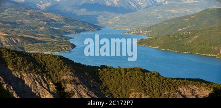 Serre-Poncon Lake with Savines-Le-Lac village and its bridge. Panoramic view on the mountains of the Durance Valley in Summer. Hautes-Alpes, France Stock Photo