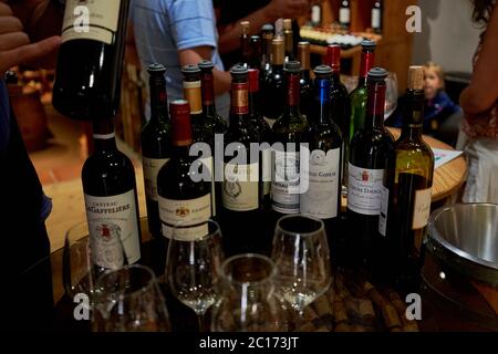 Bottles of La Gaffelière family wines lined up with tasting glasses in a Saint-Emilion wine shop, France Stock Photo