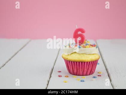 Happy birthday cup cake with pink number 6 candle on white wood table for little girl Stock Photo
