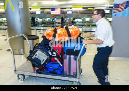 Miami Florida International Airport MIA,aviation,terminal,luggage,suitcase,baggage,stack,cart,carrier,man men male adult adults,pushing,working,work,s Stock Photo