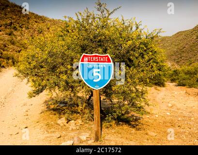 California interstate 5 traffic sign in front of desert thorn tree with gravel road fork Stock Photo