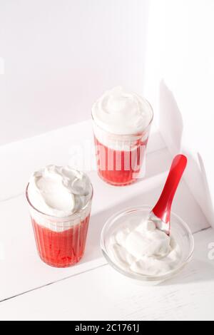Two glasses with strawberry smoothie shakes and whipping cream on white background top view.Summer refreshing drink mocktail Stock Photo