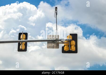 back on stop lights on metal arm with traffic camera against pretty cloudy sky Stock Photo