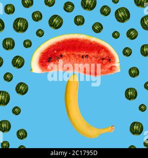 Umbrella concept of a slice of watermelon and banana on a blue background. The rain of watermelons. Creative idea of a weather forecast. Modern art Stock Photo