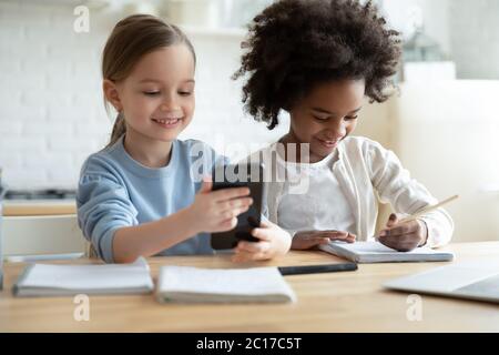 While african sister studying, another girl having fun using smartphone Stock Photo