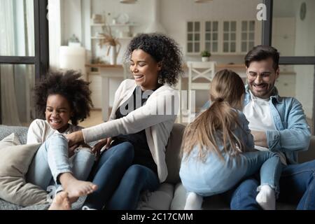 Multiracial parents tickling little daughters family having fun at home Stock Photo