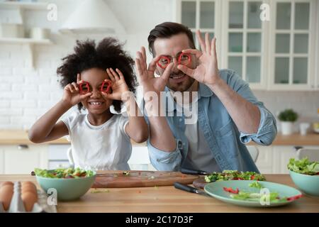 Family having fun in kitchen covering eyes with paprika circles Stock Photo