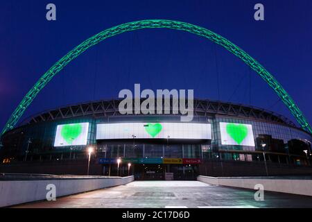 Wembley, London, UK. 14th June 2020. Wembley Stadium arch lit Green to mark the 3rd Anniversary of the Grenfell Fire. The 'Go Green For Grenfell' Campaign is to show solidarity with the survivors and remember the victims of the tragedy. 72 people were killed in the 24 story tower in West London when it was engulfed in flames in the early hours of 14 June 2017. Credit: Chris Aubrey/Alamy Live News Stock Photo