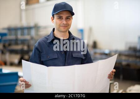 Blue dressed engineer reading a bluepring drawing in an industrial ...