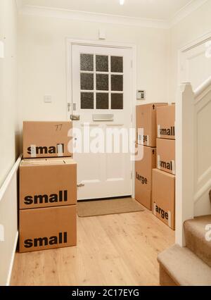 Packed and taped cardboard boxes stacked inside a room of a home, moving house, UK Stock Photo