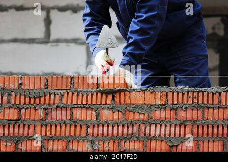 professional construction worker laying bricks and building house on industrial site. Stock Photo