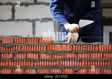professional construction worker laying bricks and building house on industrial site. Stock Photo