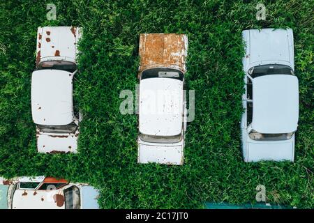 Aerial top view of old retro rusty abandoned cars in green grass, cemetery of vintage cars. Stock Photo