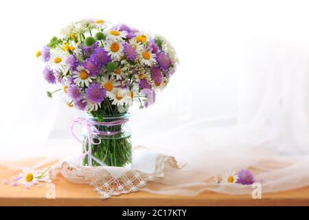Chamomiles bouquett in vase on fabric background. Stock Photo