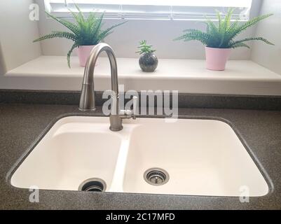 Sink with double bowl and stainless steel faucet against window of home kitchen Stock Photo