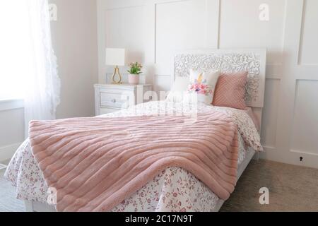 Bedroom interior with floral feminine beddings and decorative headboard on bed Stock Photo