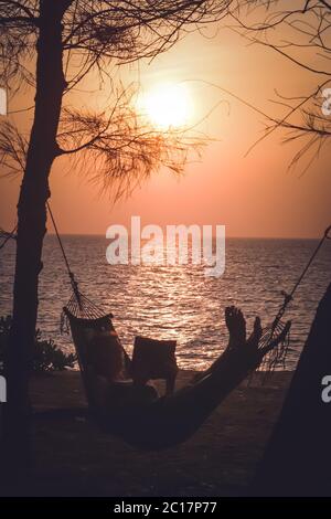 Relaxing in a hammock on a beach at sunset Stock Photo