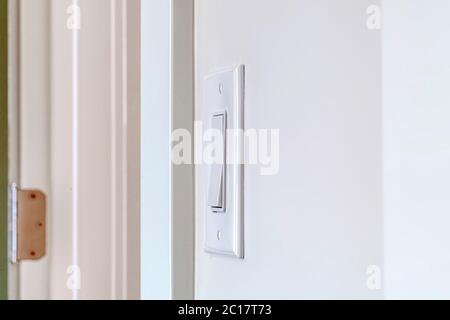 Side view of electrical rocker light switch mounted on white interior wall Stock Photo