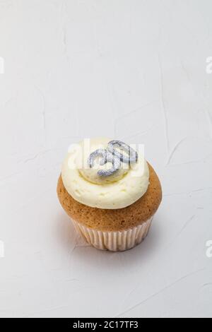 Single vanilla sponge cup cake with silver glitter number 30 on top of creamy white frosting Stock Photo