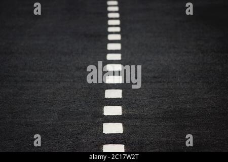 New white intermittent road markings on black asphalt. Stock Photo