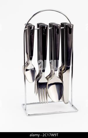 Knives, forks and spoons with black handles hanging on metal stand isolated on white background Stock Photo