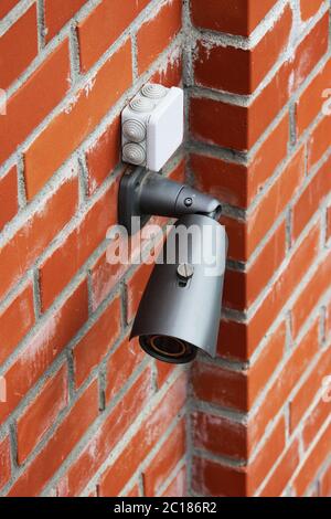 A video camera on a red brick wall protects the territory from the invasion of strangers. Stock Photo