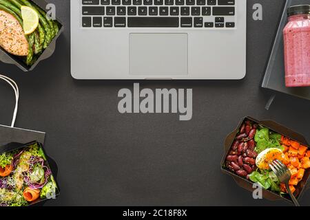 Office food delivery meal lunch boxes delivered at work on black table. Stock Photo