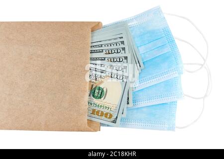 Blue medical face masks and stack of 100 USD banknotes in brown paper packet isolated on white background Stock Photo